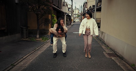 Image showing Women, friends and piggy back in city, talk and travel together on vacation, street and buildings. Japanese people, girl and outdoor in metro road, houses and urban neighborhood with chat in Tokyo