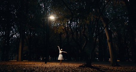 Image showing Ballet, dance and woman outdoor at night in Japan with street light, trees and creative art. Ballerina, performance and talent in dark Kyoto forest, woods or garden with spotlight in nature or park