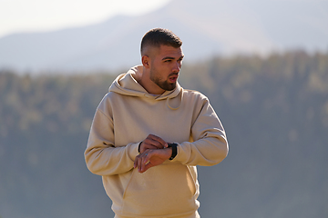 Image showing Athletic man maintains his healthy lifestyle by running through the scenic mountain and lakeside environment, showcasing a commitment to fitness and well-being