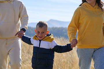 Image showing A modern family, along with their son, revels in the joy of a muddy day in nature, running and playing together, encapsulating the beauty of a healthy and active lifestyle