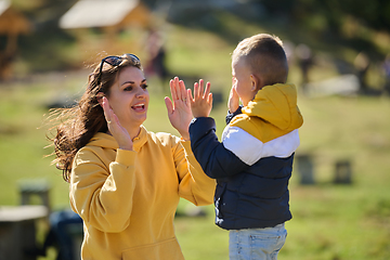 Image showing A mother and son create cherished memories as they playfully engage in outdoor activities, their laughter echoing the joy of shared moments and the bond between parent and child