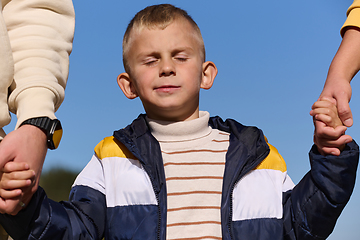 Image showing A close-up shot features a young boy walking hand in hand with his parents , as they joyfully explore the wonders of nature together, creating lasting memories of familial love and outdoor adventure