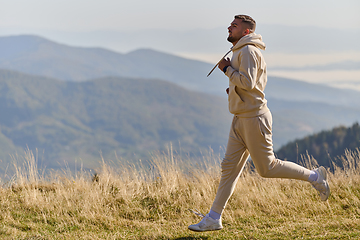 Image showing A handsome man maintains his healthy lifestyle as he runs along beautiful natural trails, embodying the essence of fitness, wellness, and vitality in the midst of scenic outdoor surroundings.