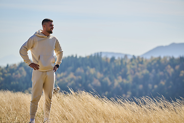 Image showing A handsome man maintains his healthy lifestyle as he runs along beautiful natural trails, embodying the essence of fitness, wellness, and vitality in the midst of scenic outdoor surroundings.