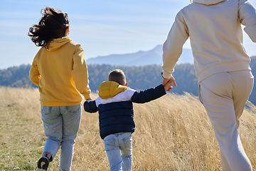 Image showing A modern family, along with their son, revels in the joy of a muddy day in nature, running and playing together, encapsulating the beauty of a healthy and active lifestyle