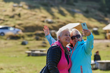 Image showing An elderly pair of women captures a timeless moment on their smartphones, blending technology with the serene beauty that surrounds them