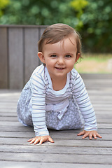 Image showing Baby girl, crawling outside and portrait on floor, child development and growth with sensory coordination. Girl, cognition and healthy in good mood, childhood or balance with arms, kid or adorable