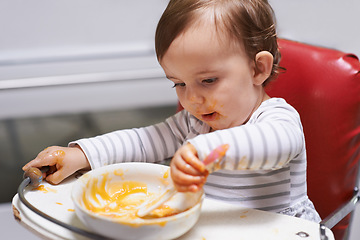 Image showing Kid eating, high chair and food, nutrition and health for childhood development and wellness. Healthy, growth and toddler person at home, vegetable or fruit, hungry baby with lunch or dinner meal