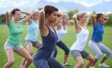 Image showing Women, stretching and squats for exercise outdoor, team and ready for workout with health and wellness. Training together on sports field, young athlete group warm up and fitness in the park
