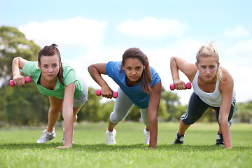 Image showing Teenager, girl with dumbbells and push up for fitness and muscle, strong athlete group outdoor for sport and bodybuilding. Portrait, exercise equipment in park and bodybuilder team workout together