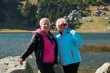 Image showing Senior women hikers standing on mountain enjoying a trekking day - Smiling climbing tourists enjoying holidays and healthy lifestyle - Freedom, success sport concept