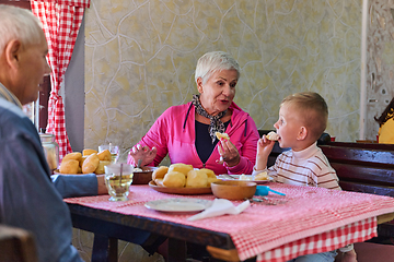 Image showing Elderly couple shares a heartwarming meal with their grandchild, creating cherished memories and enjoying the simple pleasures of family bonding in the peaceful countryside