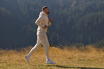 Image showing A handsome man maintains his healthy lifestyle as he runs along beautiful natural trails, embodying the essence of fitness, wellness, and vitality in the midst of scenic outdoor surroundings.