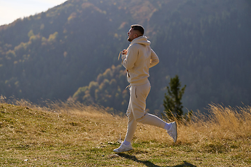 Image showing A handsome man maintains his healthy lifestyle as he runs along beautiful natural trails, embodying the essence of fitness, wellness, and vitality in the midst of scenic outdoor surroundings.