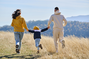 Image showing A modern family, along with their son, revels in the joy of a muddy day in nature, running and playing together, encapsulating the beauty of a healthy and active lifestyle