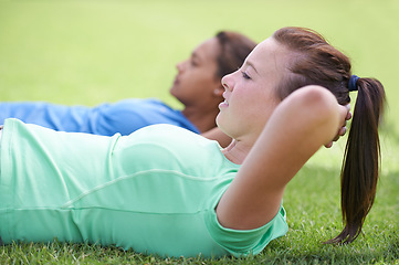 Image showing Woman, sit ups and workout on green grass for fitness or outdoor exercise together in nature. Young active female person or people in core, abs or strength training while lying on field outside