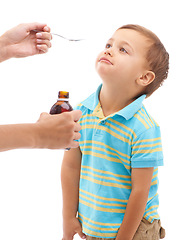 Image showing Hands, medicine bottle and spoon for boy in studio, sad and thinking with tongue by white background. Kid, mother and liquid for healthcare, pharmaceutical product and helping sick child for wellness