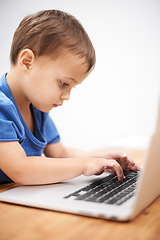 Image showing Boy kid, laptop and typing in home, reading or search for movie, cartoon or elearning for development. Child, computer and click keyboard at desk in family house for education, study or online course