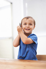 Image showing Toddler, boy and phonecall in house, happiness and communication with technology. Table, cheerful and conversation for learning, cellphone and excited for child development, mobile and digital