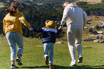 Image showing A modern family, along with their son, revels in the joy of a muddy day in nature, running and playing together, encapsulating the beauty of a healthy and active lifestyle