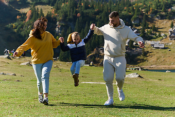 Image showing A modern family, along with their son, revels in the joy of a muddy day in nature, running and playing together, encapsulating the beauty of a healthy and active lifestyle