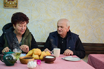 Image showing Elderly couple finds pure joy in the serene morning as they savor a cup of coffee, immersed in the tranquil beauty of nature that surrounds their rustic retreat