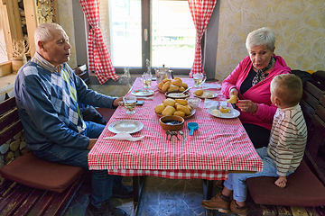 Image showing Elderly couple shares a heartwarming meal with their grandchild, creating cherished memories and enjoying the simple pleasures of family bonding in the peaceful countryside