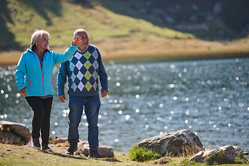 Image showing Elderly couple strolling through the breathtaking beauty of nature, maintaining their vitality and serenity, embracing the joys of a health-conscious and harmonious lifestyle