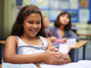 Image showing School, students or girl with a phone for texting, gossip or message notification in classroom. News, sharing or happy child with a funny meme on mobile app or social media for online distraction