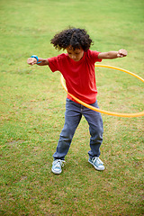 Image showing Child, playing and hula hoop on field on holiday, green grass and sunshine with energy in city. Young boy, mexican and game on playground, summer break and leisure with wellness in urban town