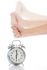 Image showing Person, hand and hitting alarm clock for alert, wakeup or deadline on a white studio background. Closeup of fist slamming down on time for stop in motion blur, schedule or management for planning