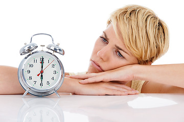 Image showing Sad woman, alarm clock and alert for wakeup or deadline on a white studio background. Upset or disappointed female person or blonde looking at time in failure, loss or bored on table on mockup space