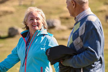 Image showing Elderly couple strolling through the breathtaking beauty of nature, maintaining their vitality and serenity, embracing the joys of a health-conscious and harmonious lifestyle