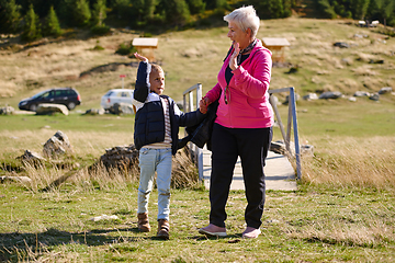 Image showing Elderly grandmother and her grandchild share a leisurely stroll through nature, enveloped in the beauty of their surroundings, fostering a bond that transcends generations