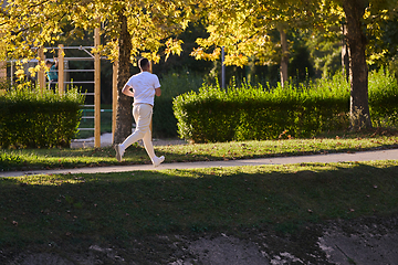 Image showing A handsome man maintains his healthy lifestyle as he runs along beautiful natural trails, embodying the essence of fitness, wellness, and vitality in the midst of scenic outdoor surroundings.