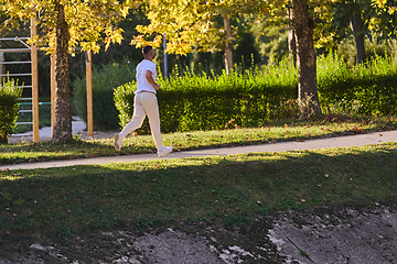 Image showing A handsome man maintains his healthy lifestyle as he runs along beautiful natural trails, embodying the essence of fitness, wellness, and vitality in the midst of scenic outdoor surroundings.