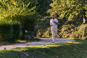 Image showing A handsome man maintains his healthy lifestyle as he runs along beautiful natural trails, embodying the essence of fitness, wellness, and vitality in the midst of scenic outdoor surroundings.