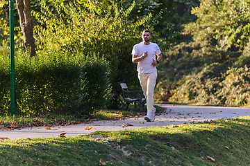 Image showing A handsome man maintains his healthy lifestyle as he runs along beautiful natural trails, embodying the essence of fitness, wellness, and vitality in the midst of scenic outdoor surroundings.