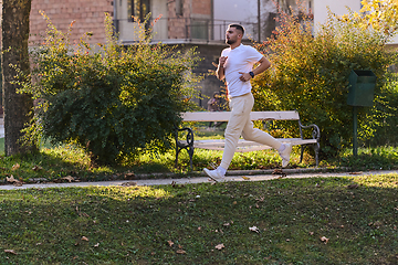 Image showing A handsome man maintains his healthy lifestyle as he runs along beautiful natural trails, embodying the essence of fitness, wellness, and vitality in the midst of scenic outdoor surroundings.