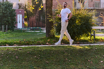 Image showing A handsome man maintains his healthy lifestyle as he runs along beautiful natural trails, embodying the essence of fitness, wellness, and vitality in the midst of scenic outdoor surroundings.