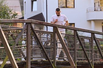 Image showing A handsome man maintains his healthy lifestyle as he runs along beautiful natural trails, embodying the essence of fitness, wellness, and vitality in the midst of scenic outdoor surroundings.