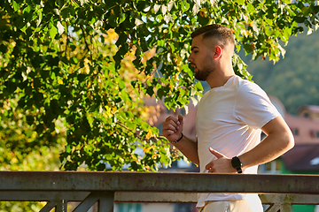 Image showing A handsome man maintains his healthy lifestyle as he runs along beautiful natural trails, embodying the essence of fitness, wellness, and vitality in the midst of scenic outdoor surroundings.