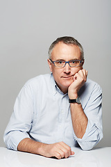 Image showing Bored, portrait and senior businessman in a studio with pride for legal corporate career. Glasses, table and professional elderly male lawyer with tired face expression isolated by gray background.