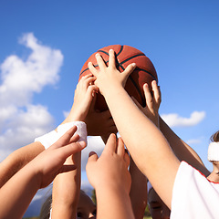 Image showing People, hands and basketball in team sports for motivation, unity or community with blue sky background. Closeup group of players holding ball up in air for friendly match or outdoor game in nature