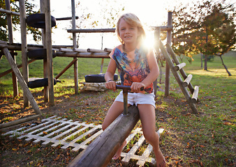 Image showing Happy girl, portrait and riding seesaw in park sunset for fun holiday, weekend or outdoor break in nature. Face of female person, kid or child smile on playground for childhood activity outside