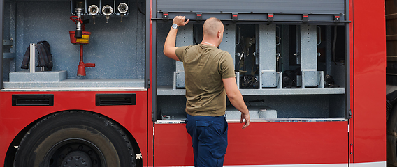 Image showing A dedicated firefighter preparing a modern firetruck for deployment to hazardous fire-stricken areas, demonstrating readiness and commitment to emergency response