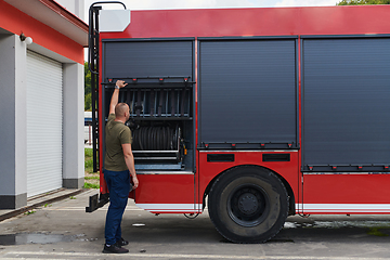 Image showing A dedicated firefighter preparing a modern firetruck for deployment to hazardous fire-stricken areas, demonstrating readiness and commitment to emergency response