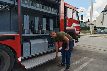 Image showing A dedicated firefighter preparing a modern firetruck for deployment to hazardous fire-stricken areas, demonstrating readiness and commitment to emergency response