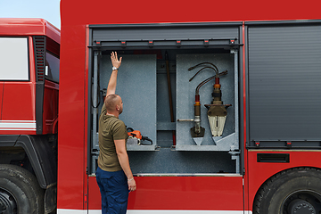 Image showing A dedicated firefighter preparing a modern firetruck for deployment to hazardous fire-stricken areas, demonstrating readiness and commitment to emergency response