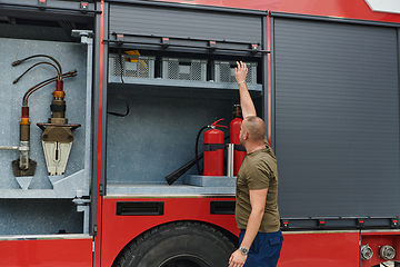 Image showing A dedicated firefighter preparing a modern firetruck for deployment to hazardous fire-stricken areas, demonstrating readiness and commitment to emergency response